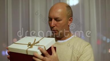 人打开礼盒.. 他脸上闪着灯光。 成人白种人眨眼和打开礼品盒。 令人惊讶的礼物